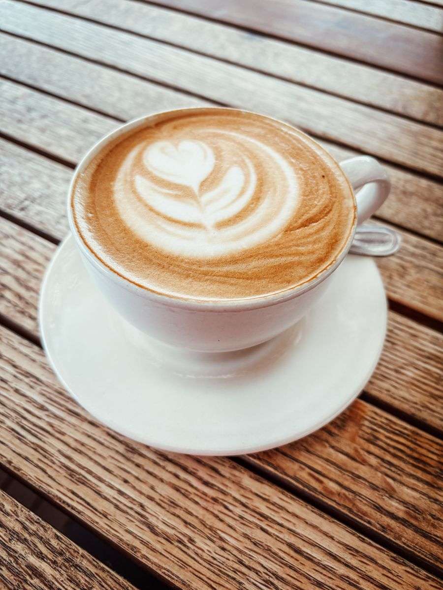 A cappuccino with heart-shaped latte art on a wooden cafe table