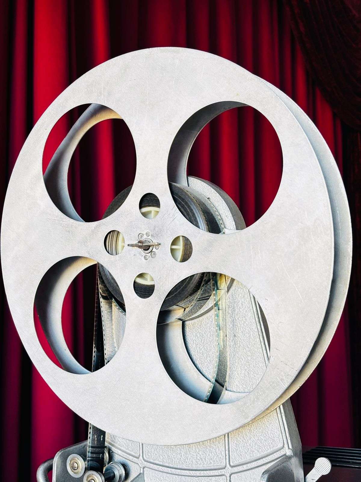A film reel in front of red theater curtains, evoking a movie premiere