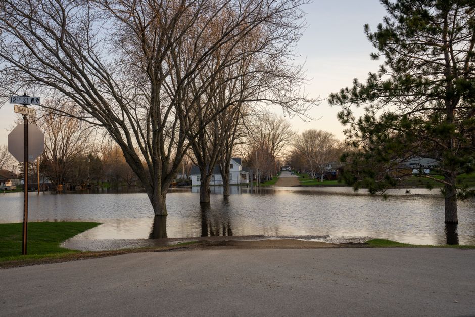 A flooded residential street with standing water following heavy spring storms