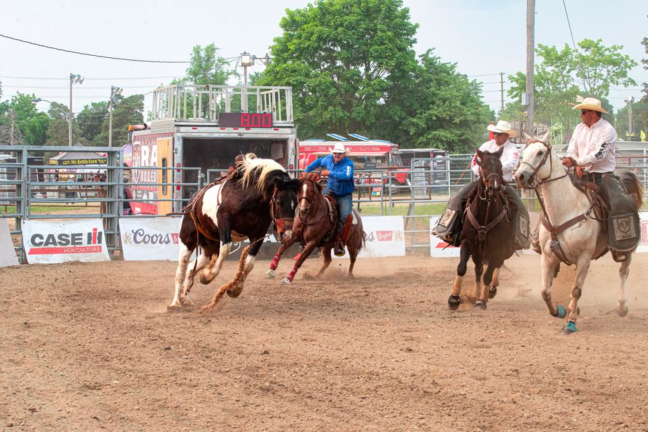 A rodeo scene with horses and riders similar to the Jennifer Claire Moore Foundation Rodeo in Foley
