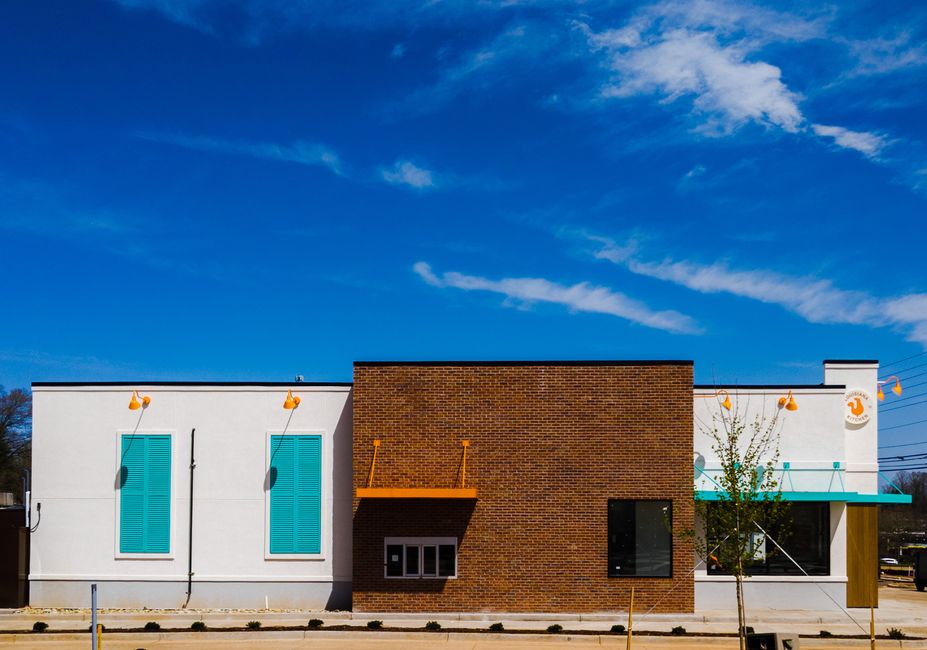 Exterior of a newly built fast-casual chicken finger restaurant with outdoor patio seating