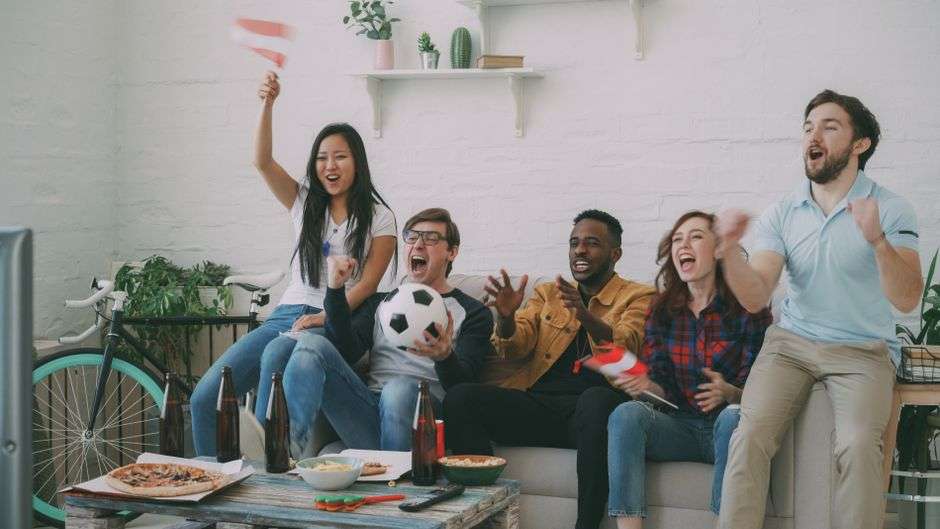 Friends and neighbors cheering while watching a football game together at a restaurant