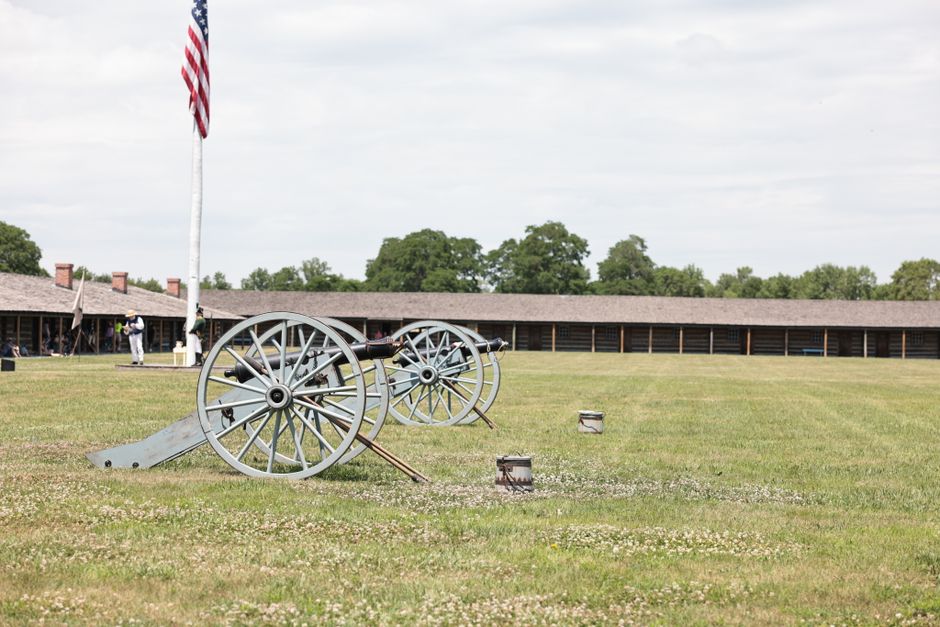 Reenactors in Confederate uniforms setting up camp near a historic coastal fort