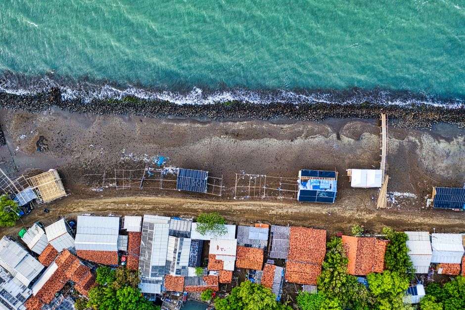 Rows of large elevated beach houses along a coastal community shoreline