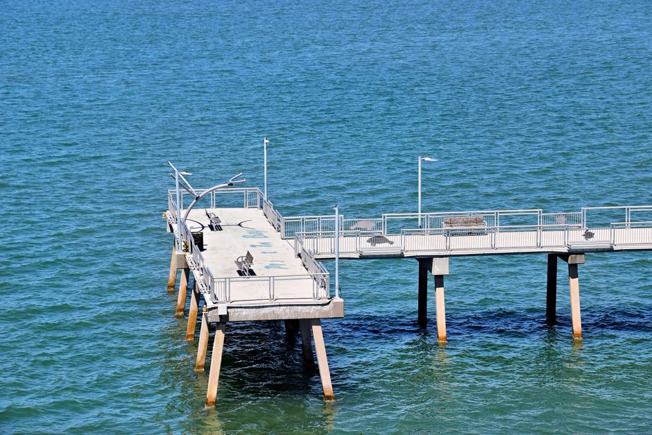 A wooden fishing pier extending into a coastal bay