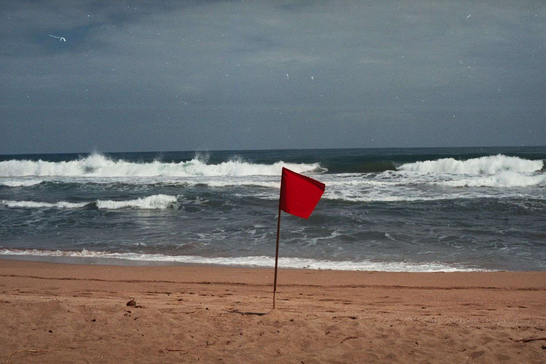 Red warning flag signaling dangerous surf conditions on a beach