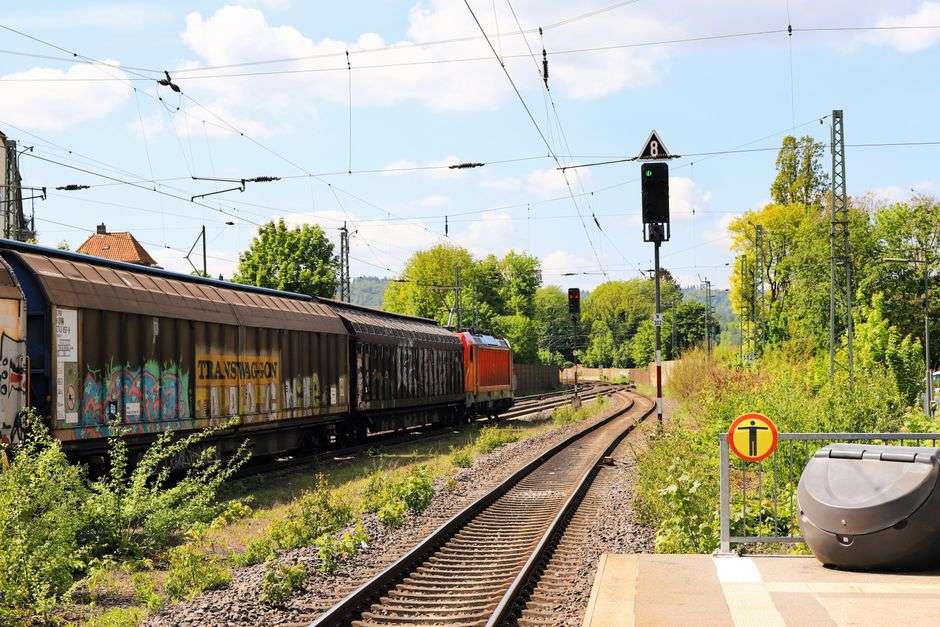 A freight train travels along railroad tracks through a green, rural landscape