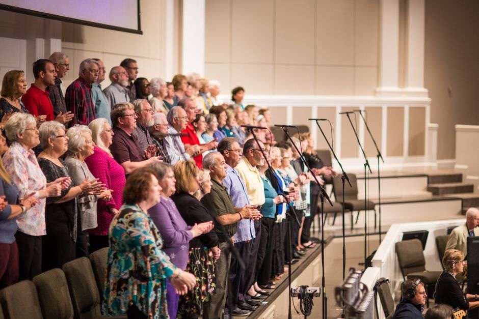 A men's chorus performs together on stage during a fundraiser concert