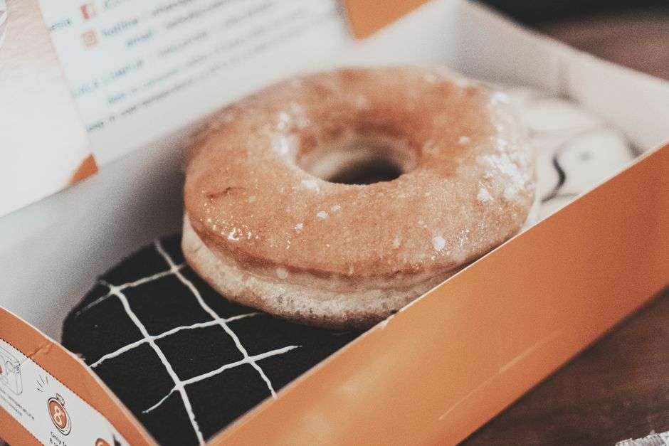 A glazed doughnut sits in an open box, similar to those sold by a roadside vendor in West Mobile