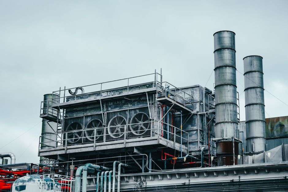 Exterior of an industrial manufacturing facility with metal piping, similar to the type of facility being upgraded in Grand Bay