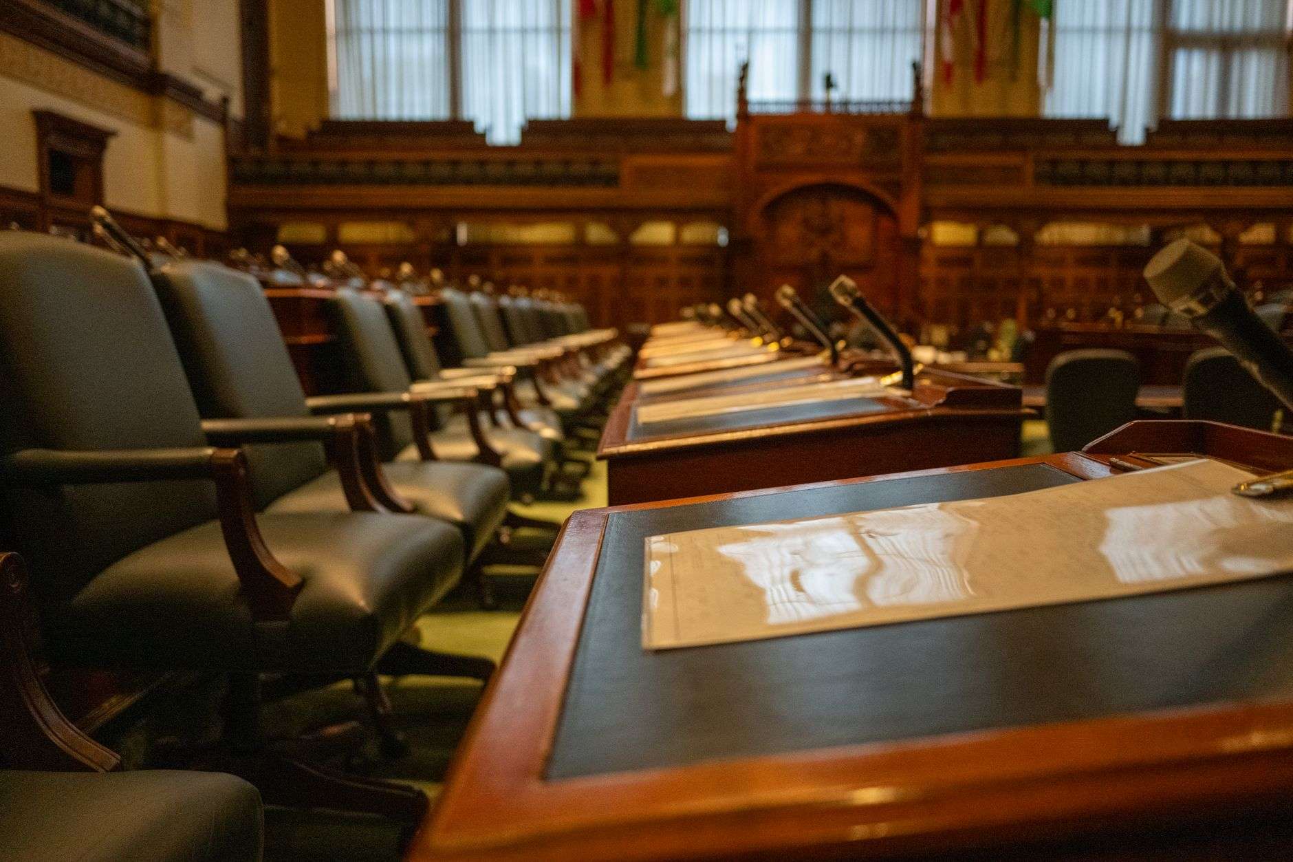 Empty government meeting chamber with rows of desks and microphones