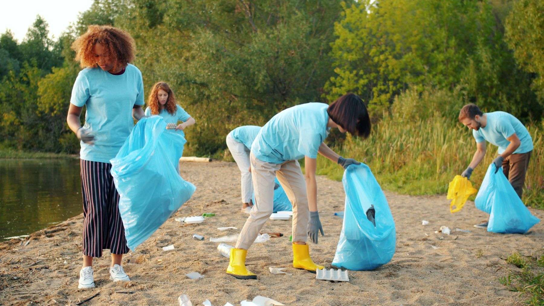Group of volunteers collecting litter along a sandy Gulf Coast beach during a cleanup event