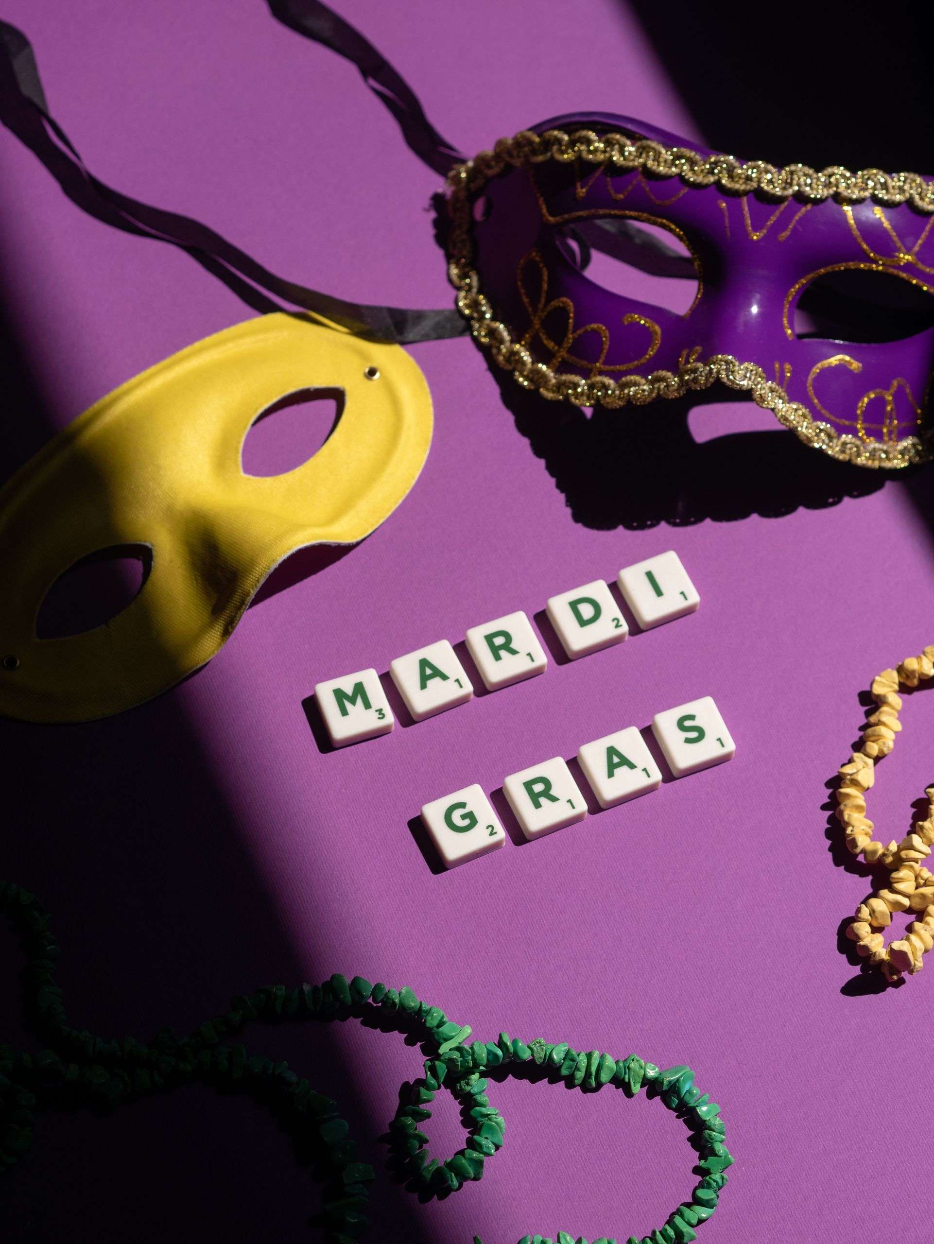 Colorful Mardi Gras mask and beads on a purple background