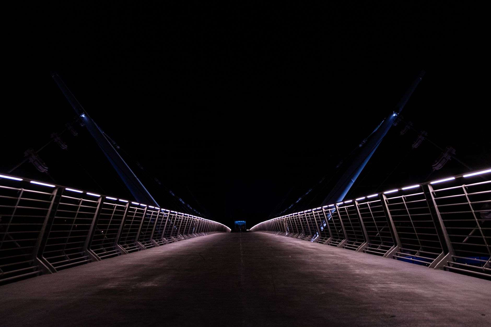 Illuminated pedestrian bridge spanning water at night