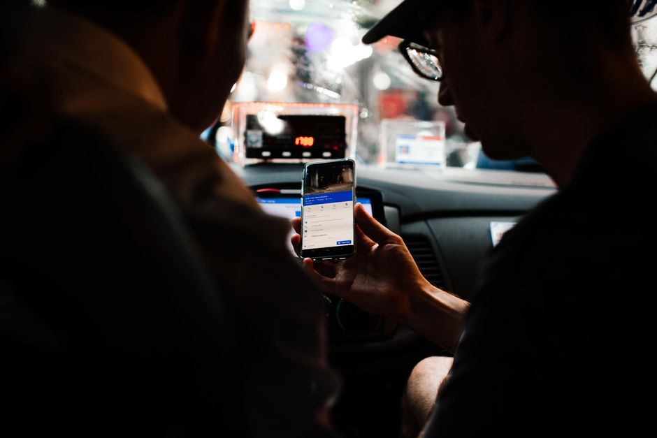 Person using a rideshare app on a smartphone near a car
