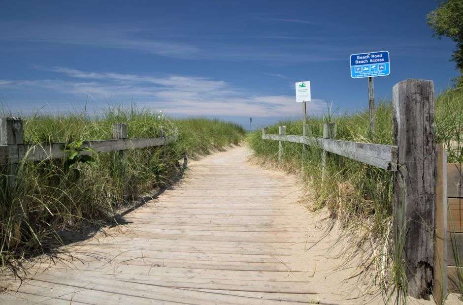A wooden boardwalk winds through beach dunes toward the Gulf of Mexico shoreline