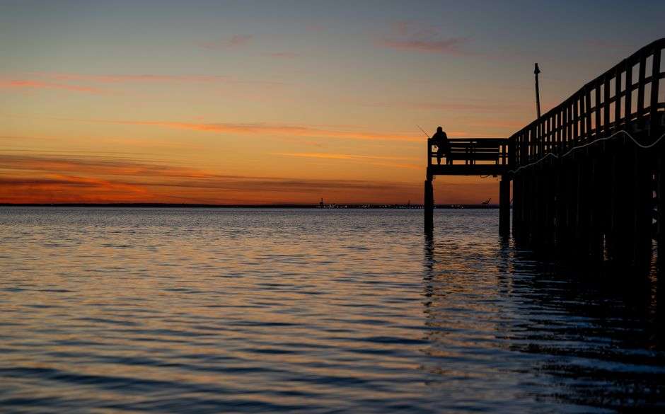 Angler fishing from a pier over the Gulf of Mexico at dusk