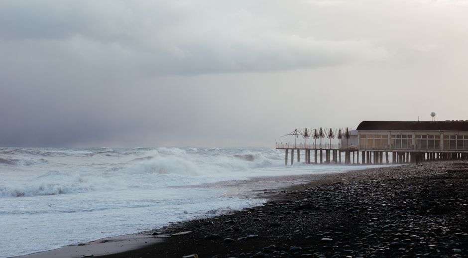 Waves crash near a Gulf Coast pier under stormy skies during a tropical storm