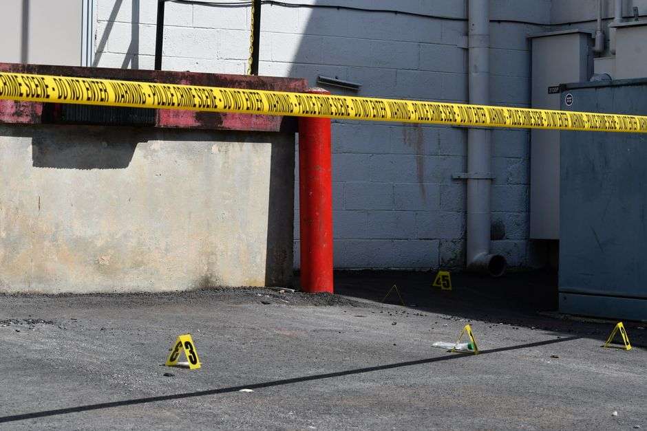 Crime scene tape stretched across a sunlit area during a police investigation