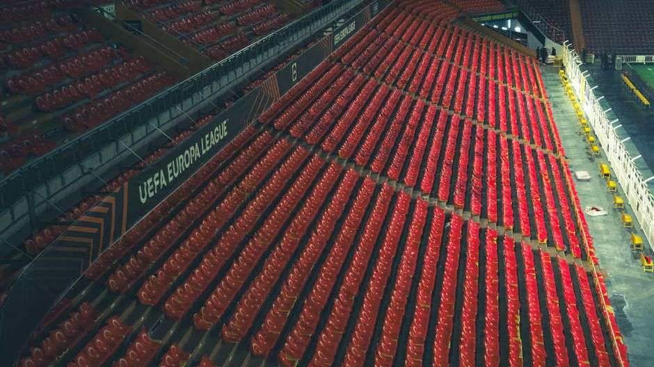 Rows of empty stadium seating illustrating reduced attendance capacity at a college football venue