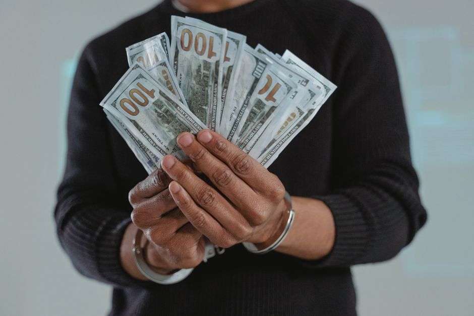Handcuffed hands holding cash, representing a federal fraud case