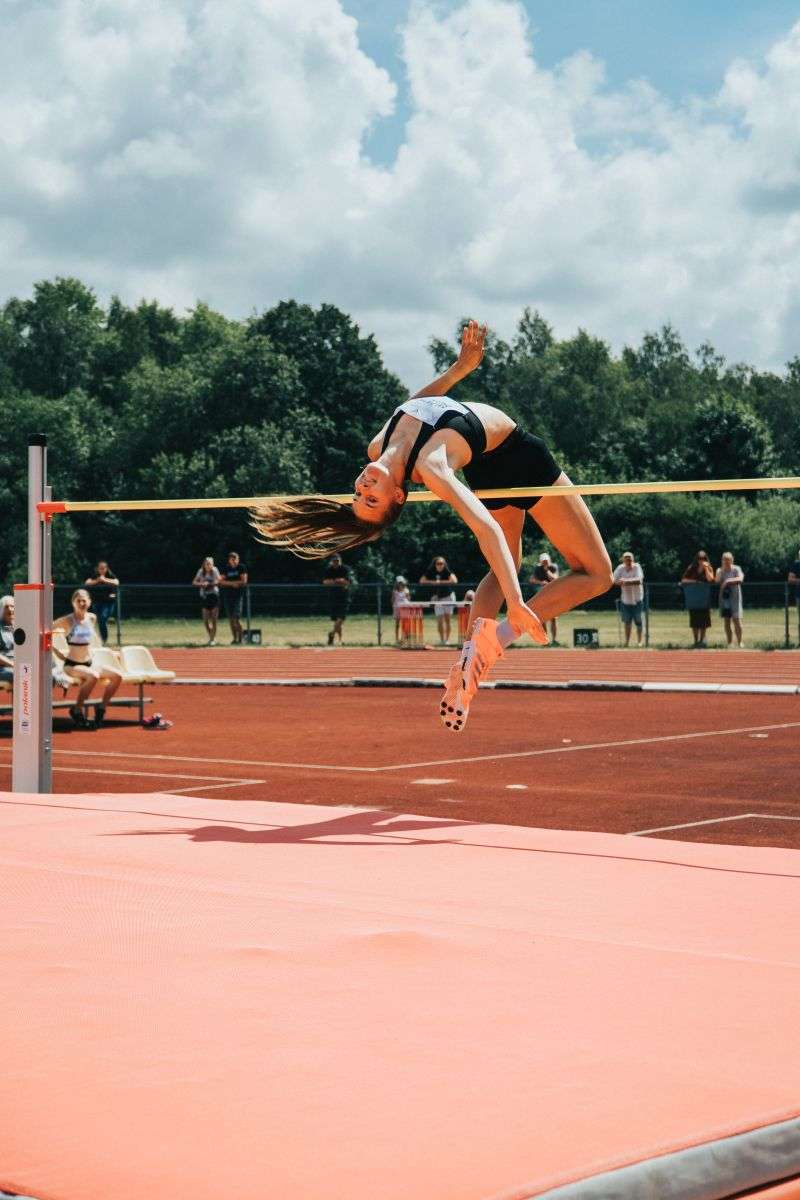 Female track and field athlete clearing the bar during a high jump competition