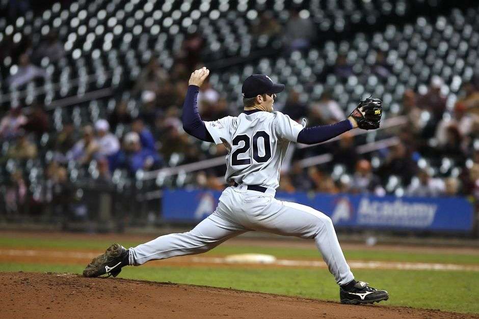 A high school baseball pitcher winds up to deliver a pitch during a game
