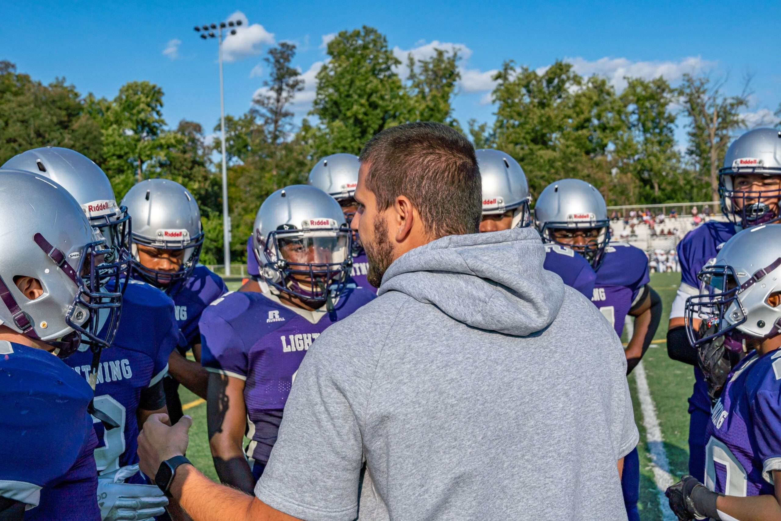 High school football coach directing players on the field