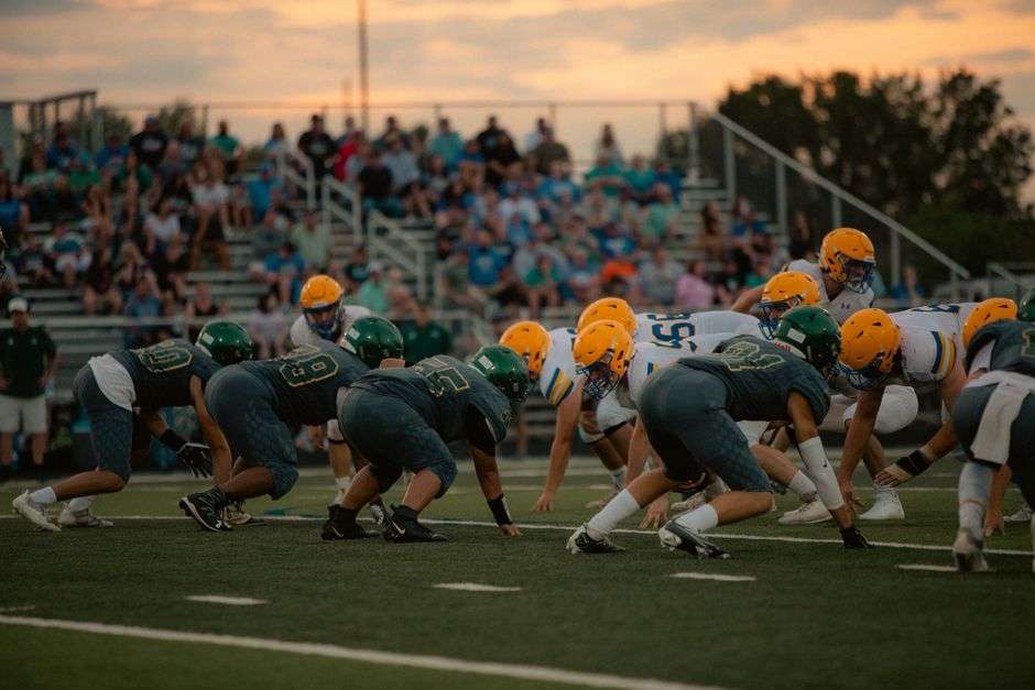 Players compete in a high school football game under the lights on a Friday night
