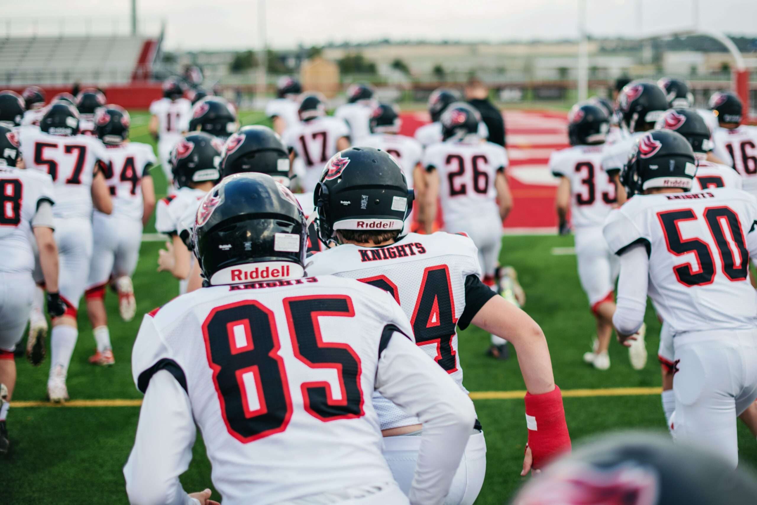 High school football players in uniform practicing on the field