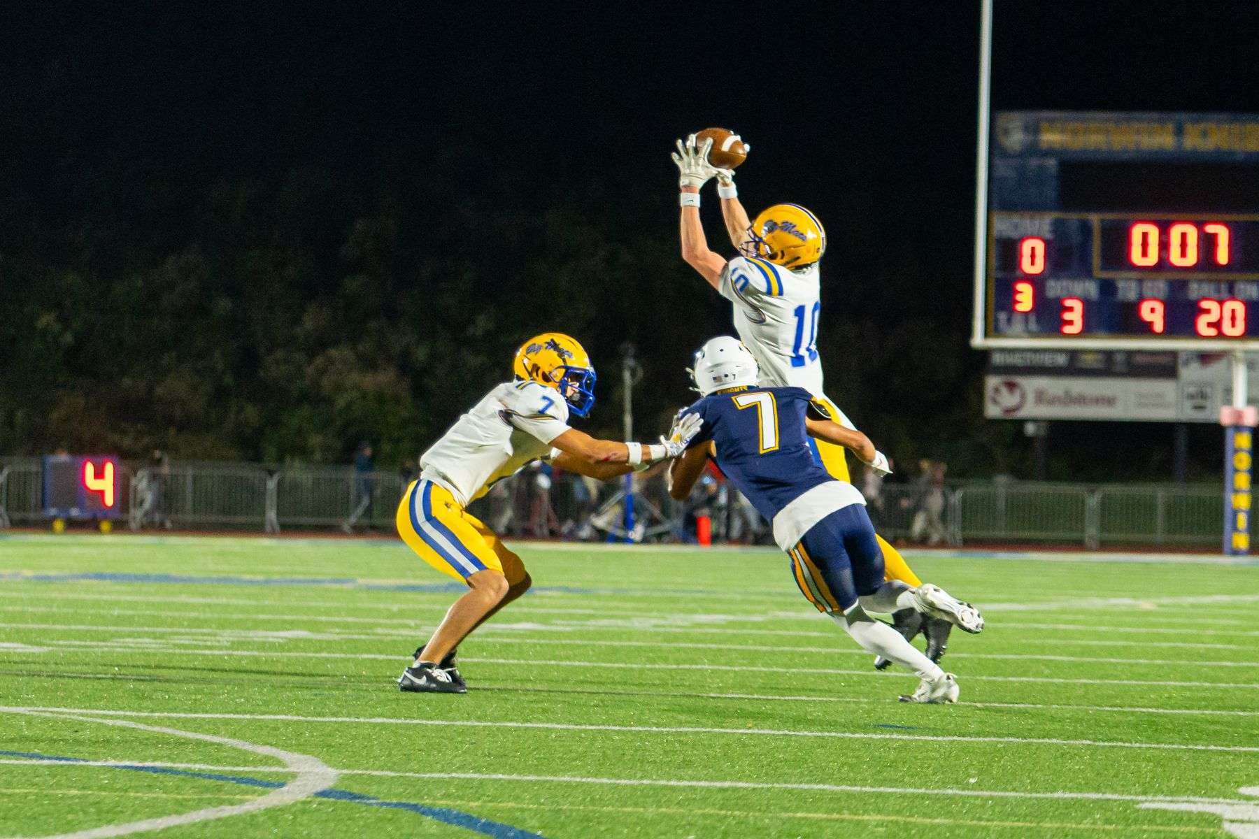 High school football players competing for the ball during a night game