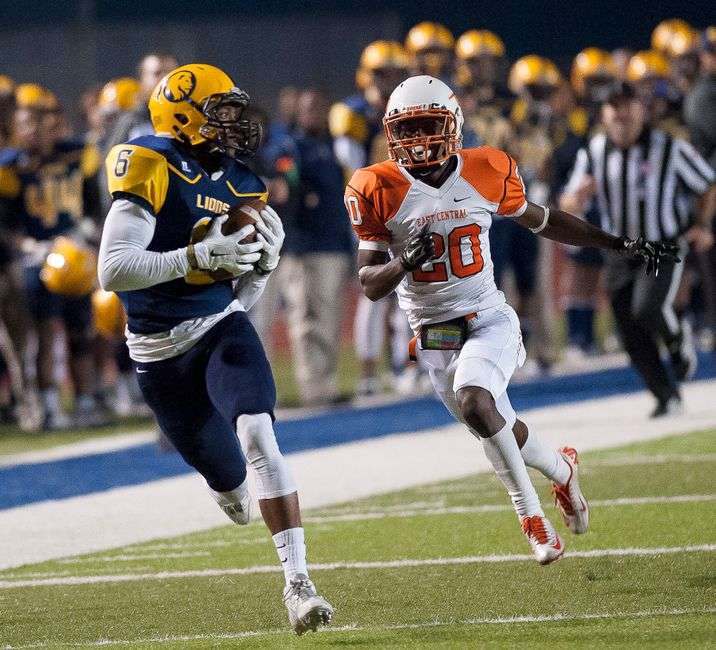 A high school football running back carries the ball past defenders
