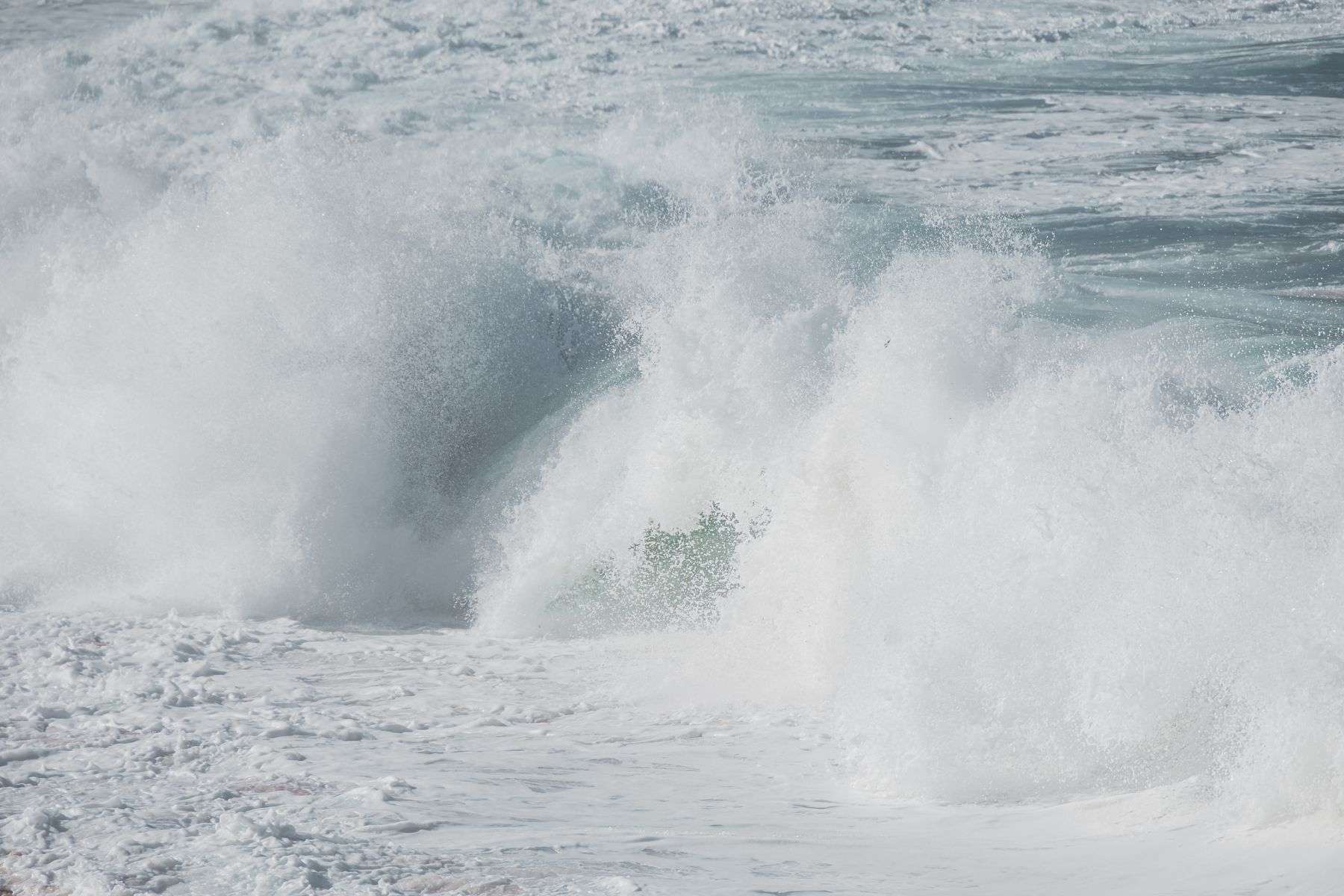 Powerful ocean waves breaking along the shoreline under a coastal flood advisory