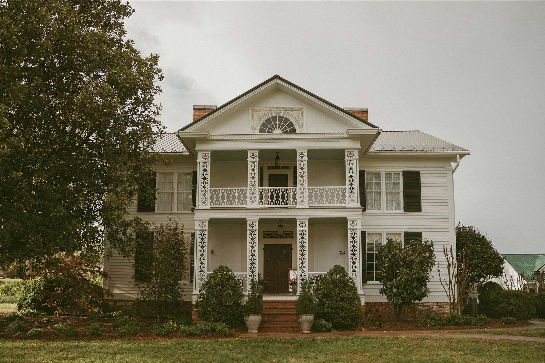 Historic white colonial-style house with a wraparound porch