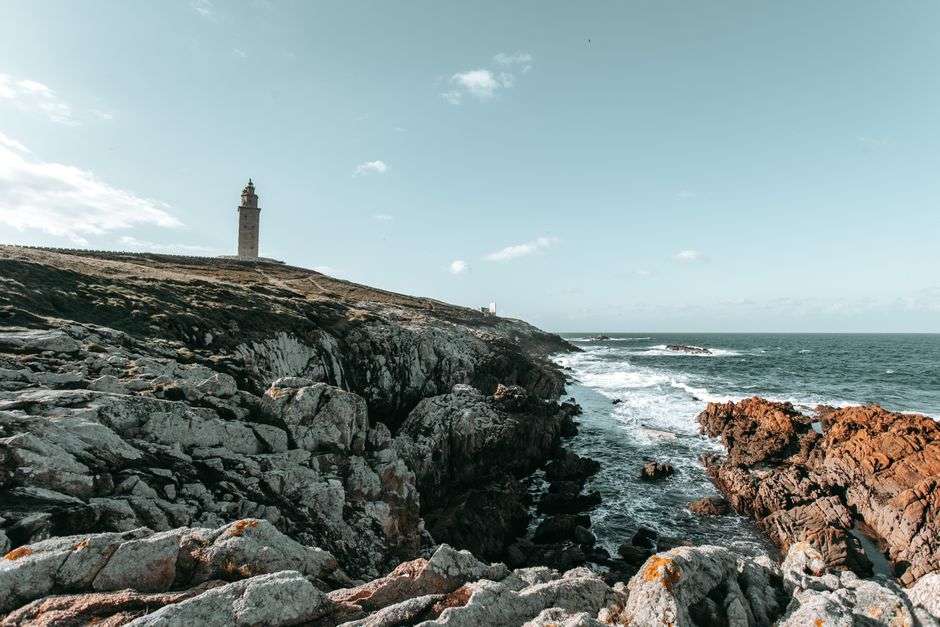 Historic lighthouse standing along a rugged coastline near the water
