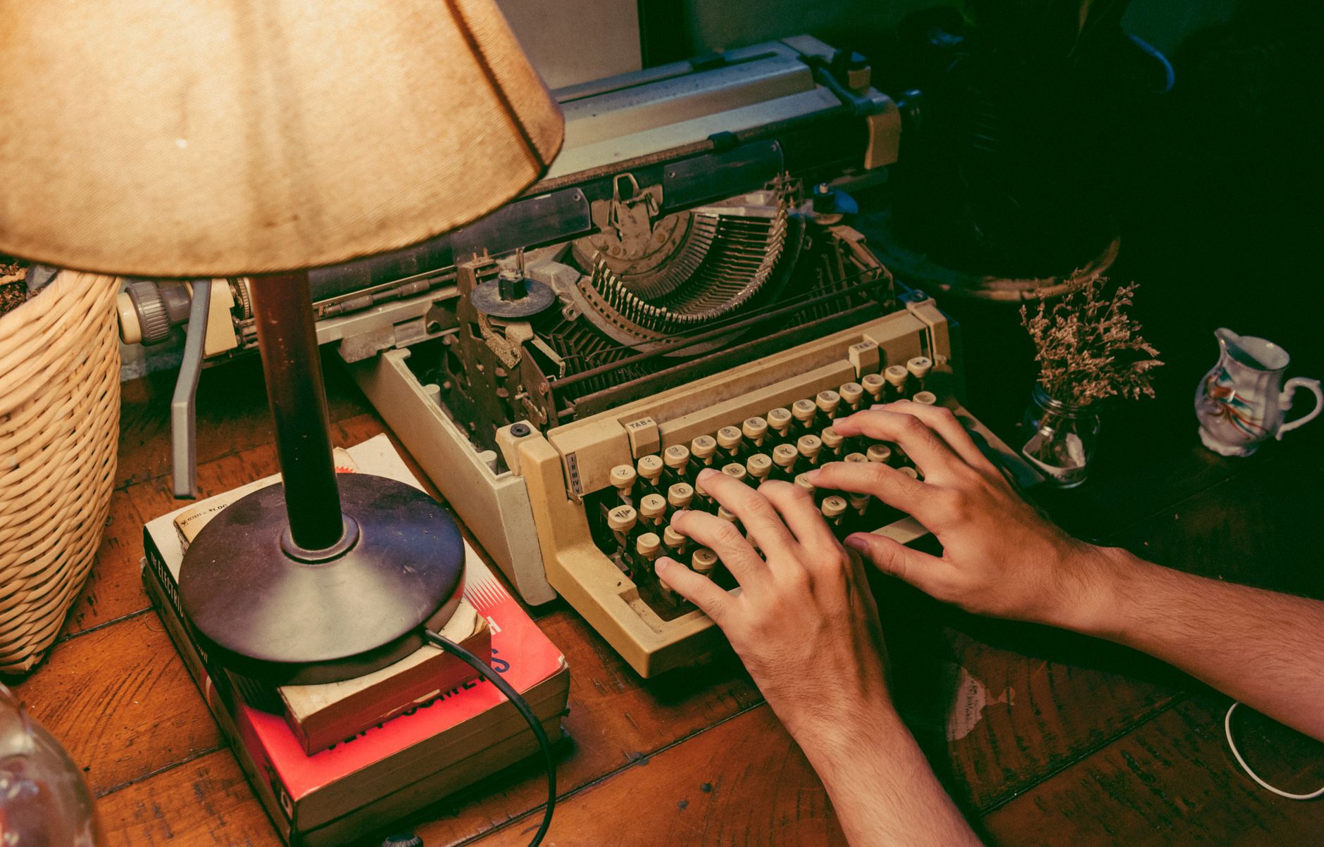 A vintage typewriter on a cluttered desk in a dimly lit apartment