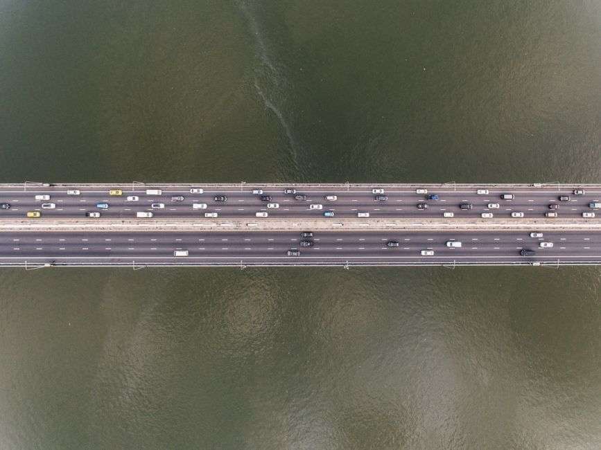 Vehicles moving in heavy traffic on a bridge crossing a body of water
