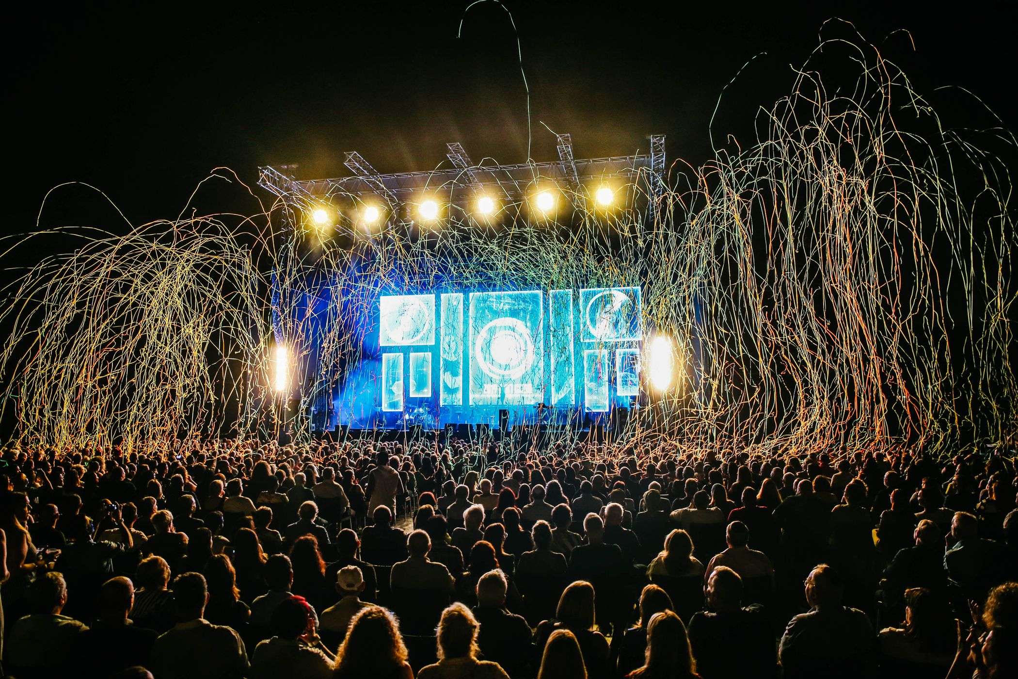 Bright stage lights illuminate a crowd at an outdoor country music concert