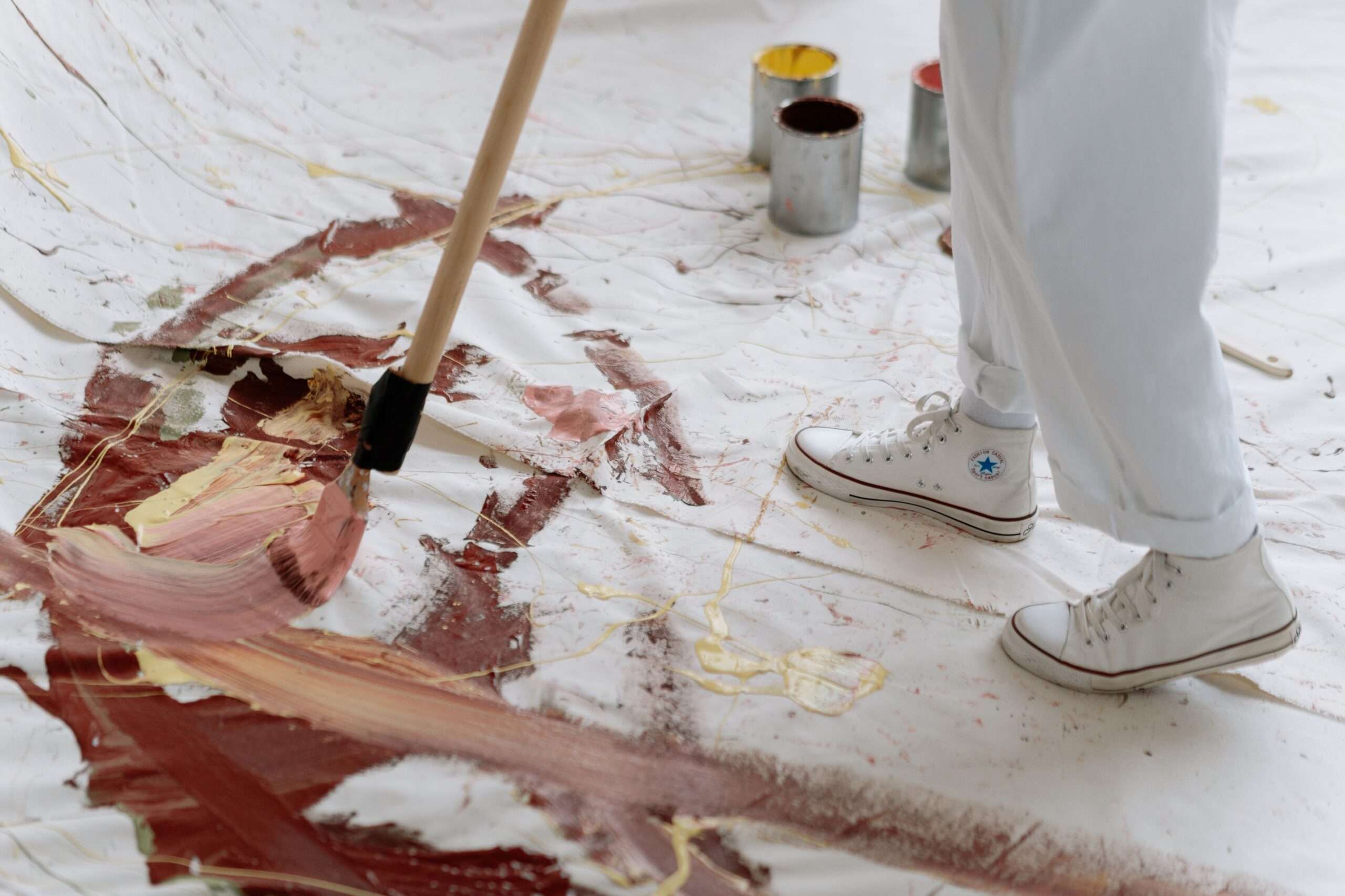 Artist applying brush strokes of paint to a large canvas in a studio