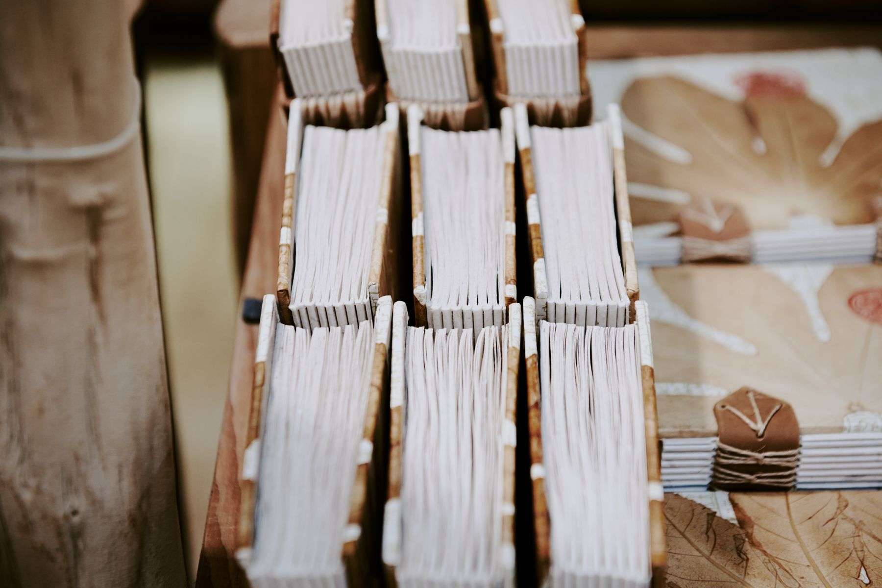 Stack of handmade paper notebooks and bound books arranged on a wooden table