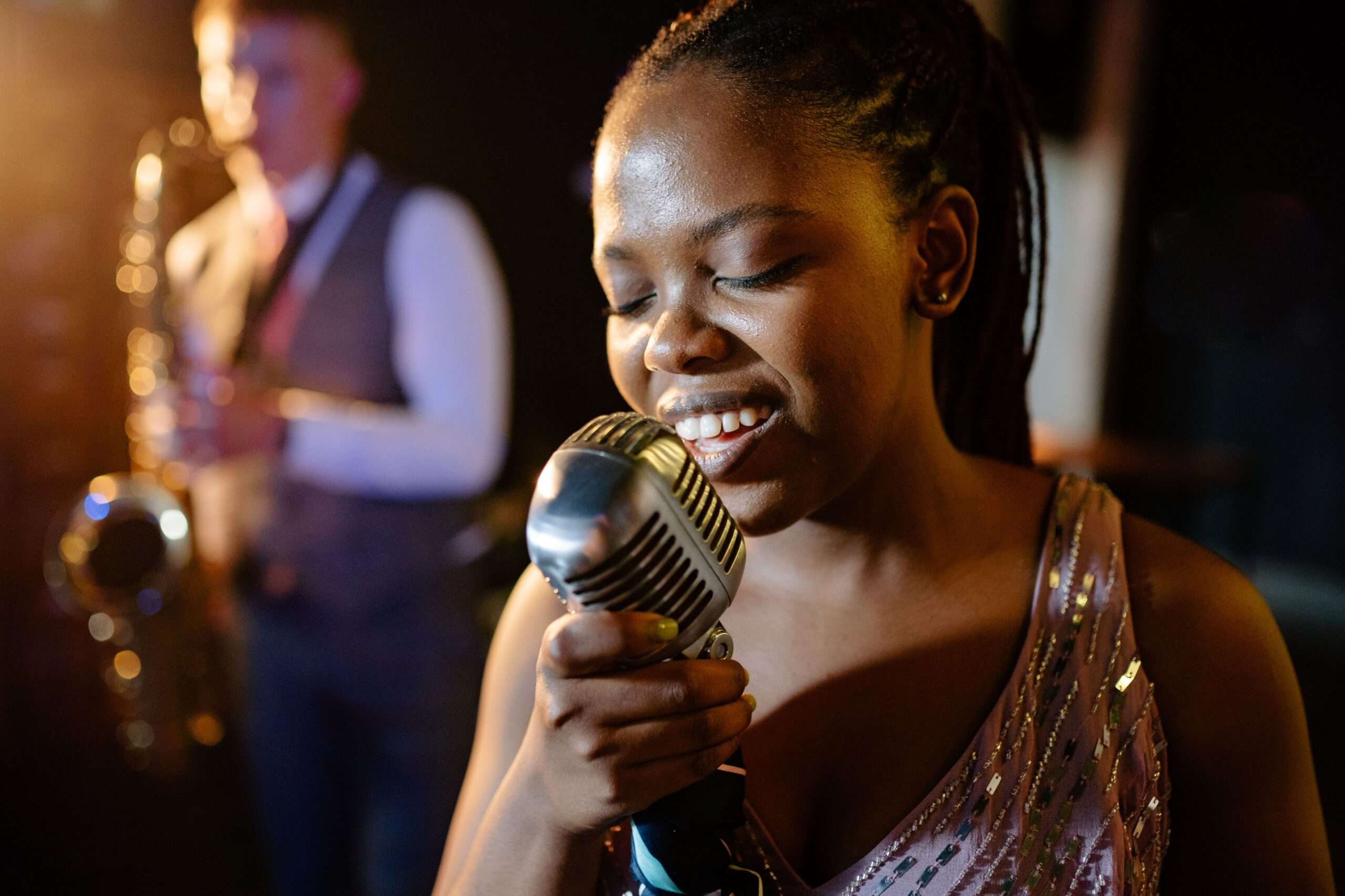 A smiling female jazz vocalist singing passionately with a live band on stage