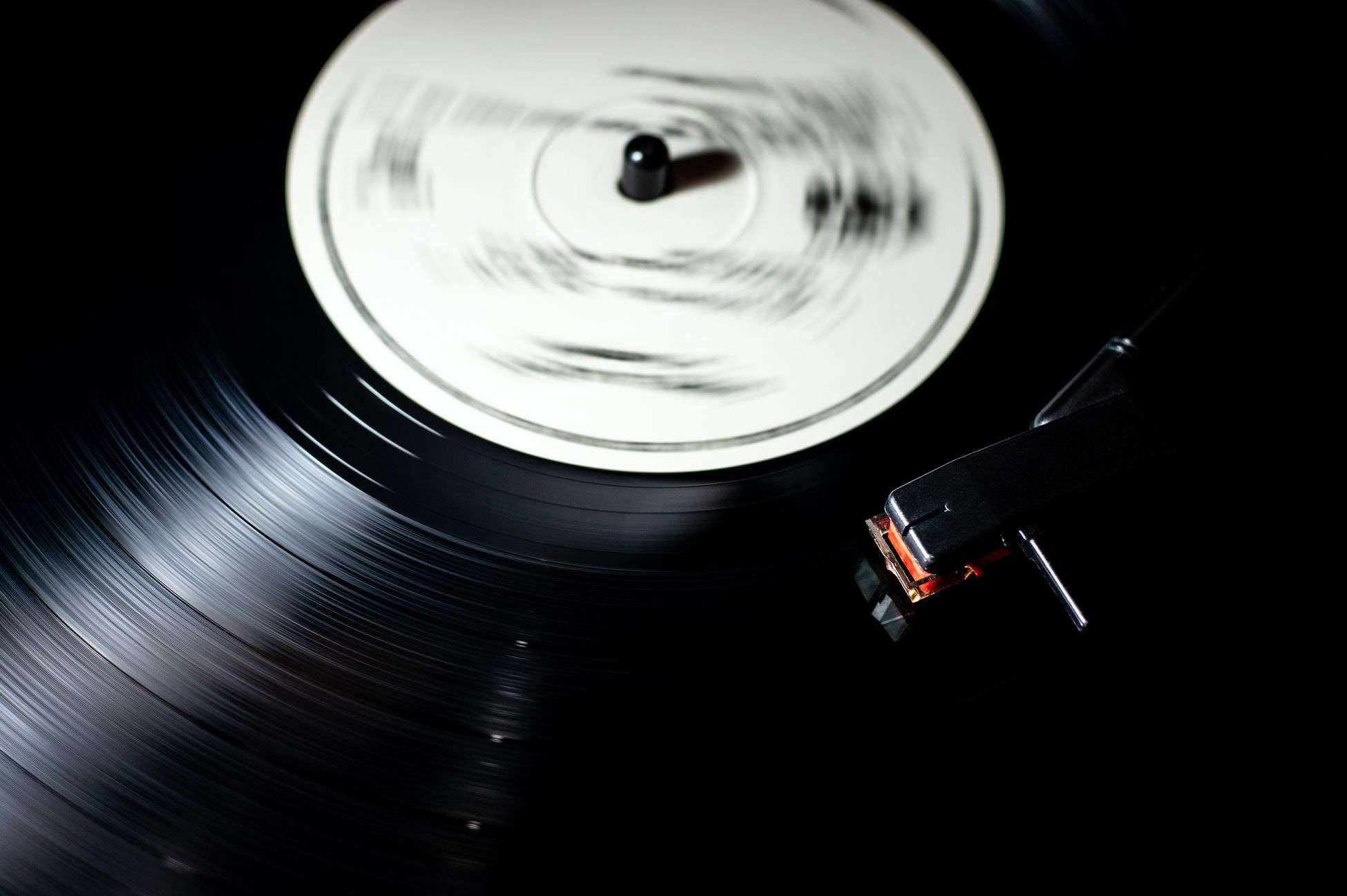 Close-up of a black vinyl record spinning on a turntable with tonearm and needle visible