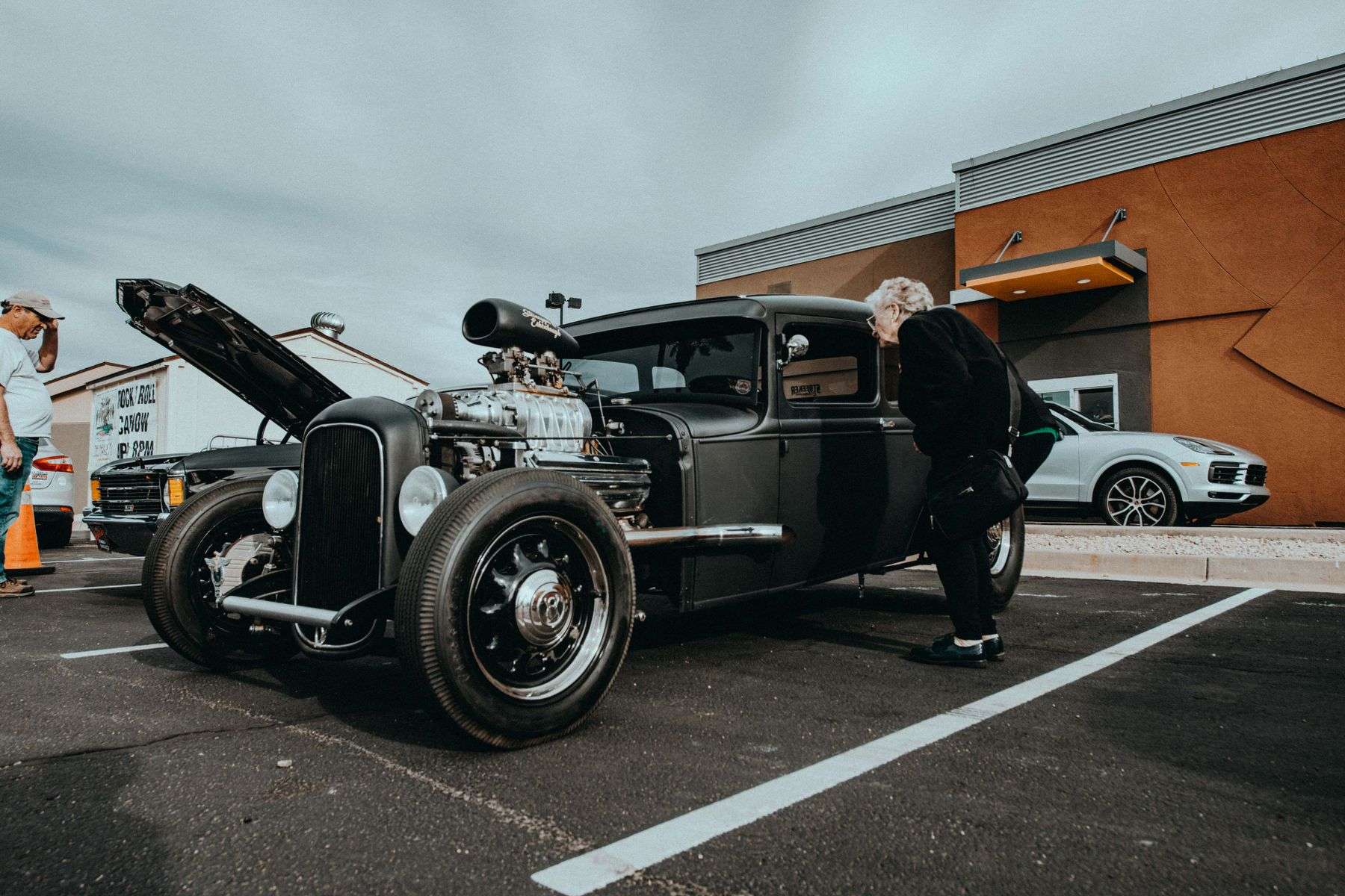 A classic hot rod with a chrome-trimmed body on display outdoors at a car show