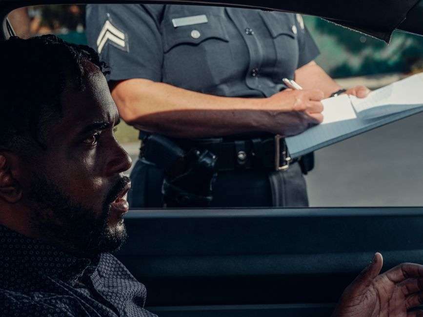 A law enforcement officer speaks with a driver during a roadside traffic stop on a highway
