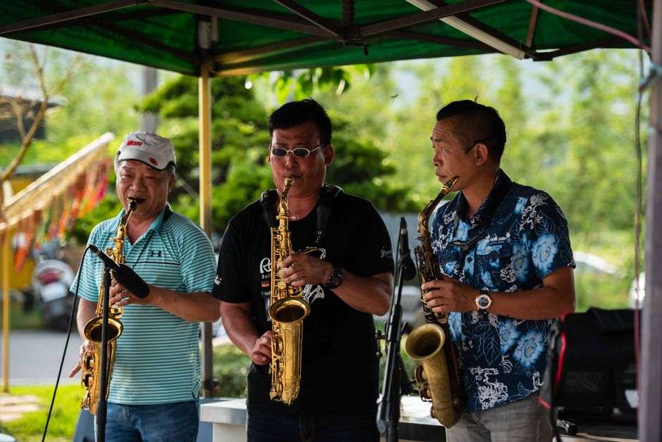 Musicians play saxophones together outdoors at a jazz festival
