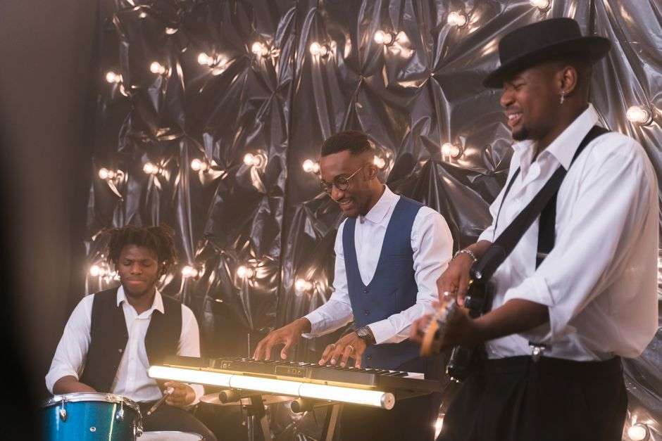 A jazz trio performs on a brightly lit concert stage during a holiday show