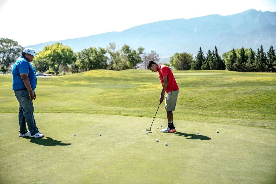Golfers practice putting on a sunny golf course