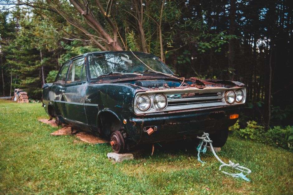 A tow truck hauling away an inoperable, abandoned-looking car