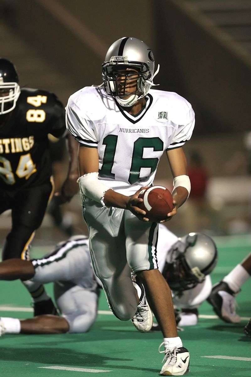 A quarterback preparing to pass during a night football game under stadium lights