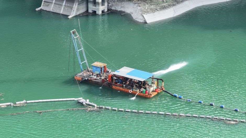 A barge dredges sediment from a lake to clear waterways for boating